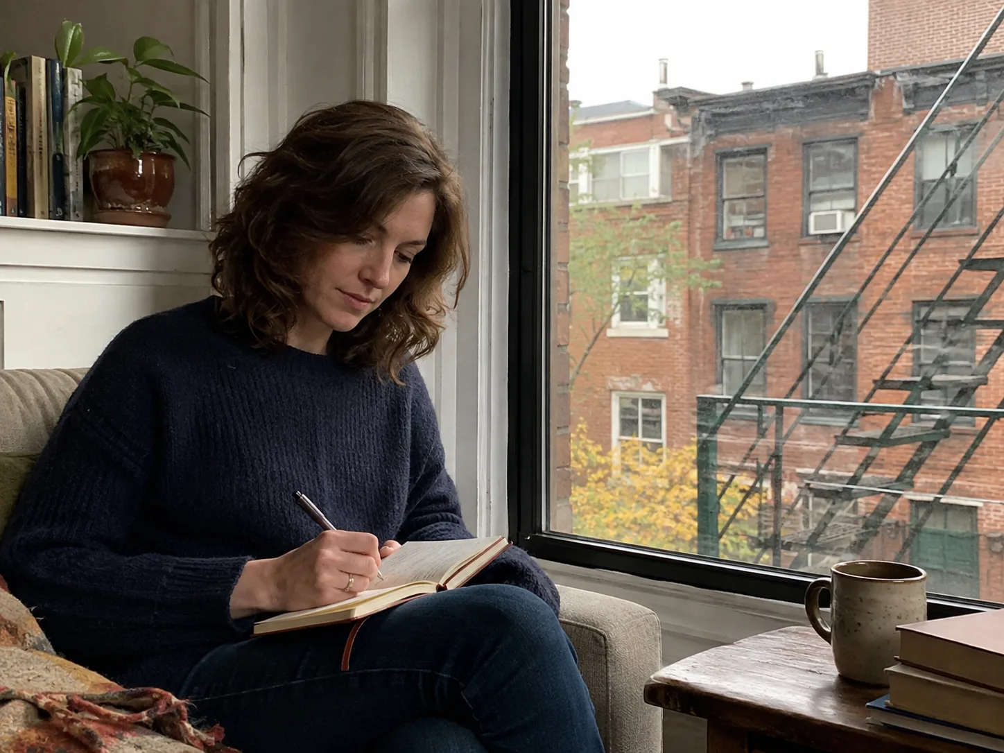 Claire writing in her diary beside her Brooklyn apartment window